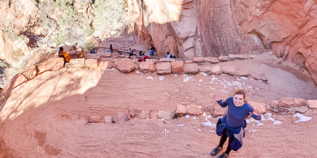 A woman stands on the path winding back and forth down the canyon