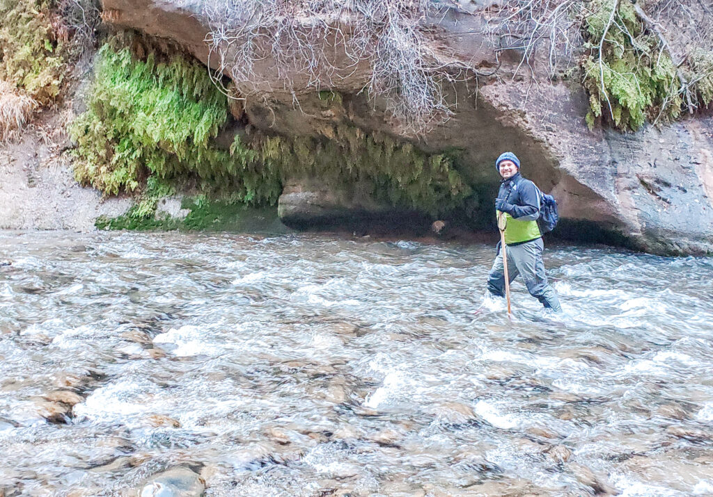 A man in a dry suit hiking the white water area of the narrows. The dry-suits are nessecaties for hiking the narrows.