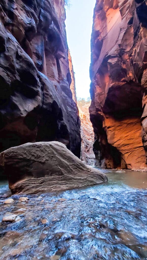A slot canyon with dark colors and large pieces of rock making assorted indents.