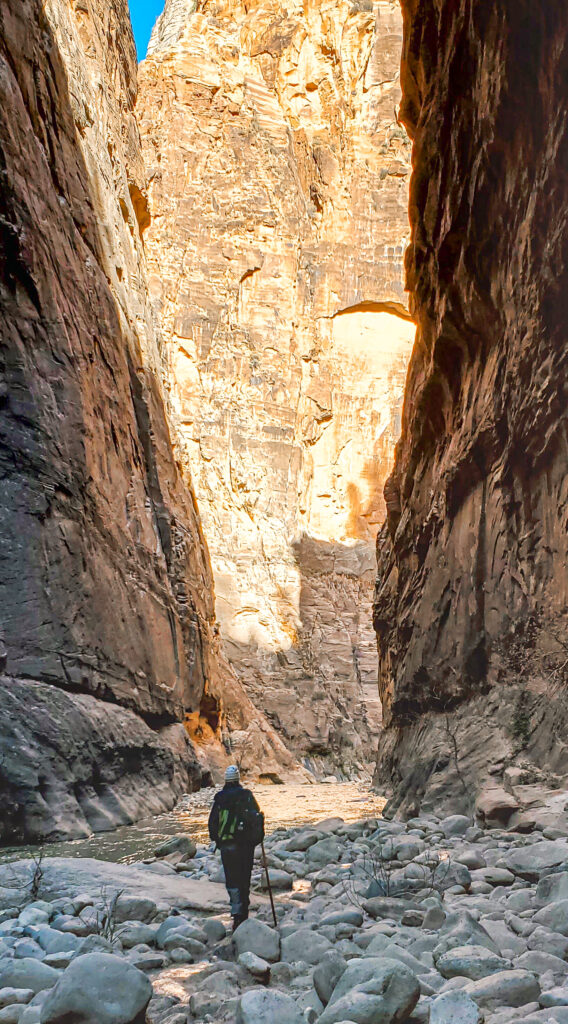 People standing on rocks looking out at the river and slot canyon in the narrows.