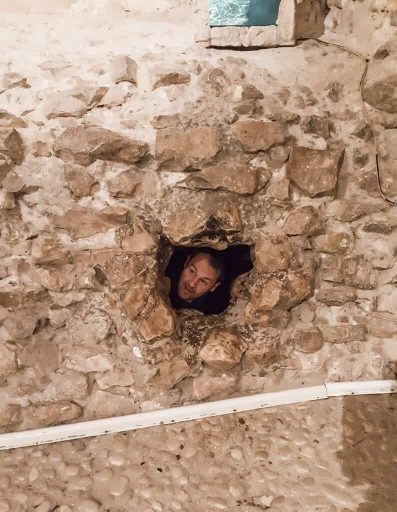 The wall of a stone courtyard with a man's head sticking out through a window.