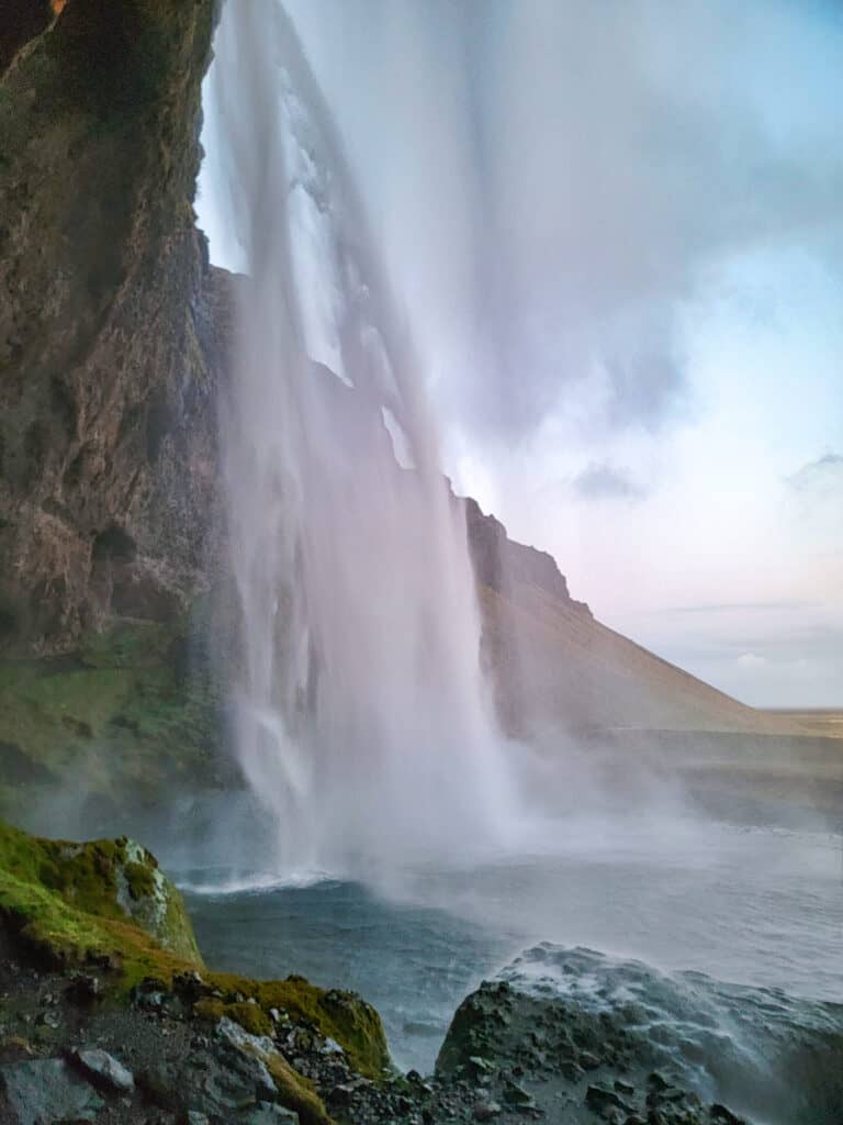 Waterfall cascades down into a blue pool.