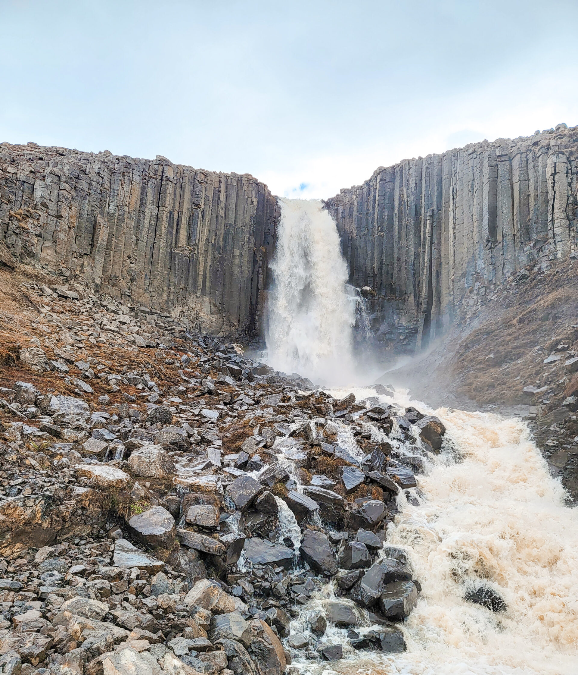 A huge waterfall with lots of white water and crashes down with rocks on both sides with sheet rocks.
