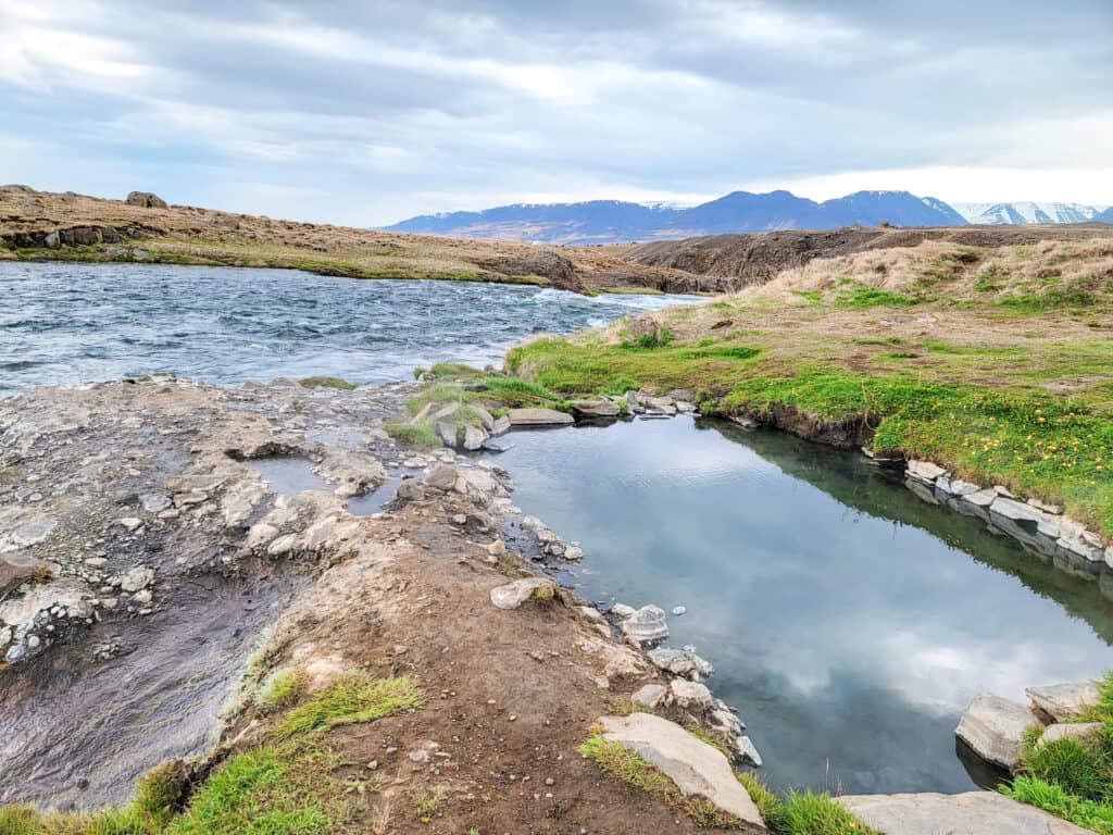 A river goes downstream with a little small hot pot at the very side of the river.