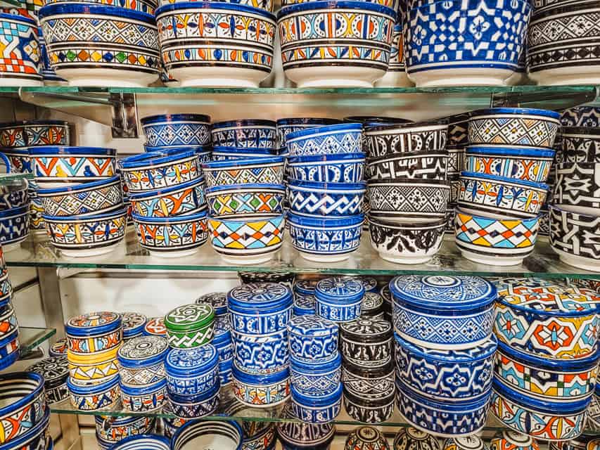 Decorated, painted bowls fill shelves in a Marrakech market shop.