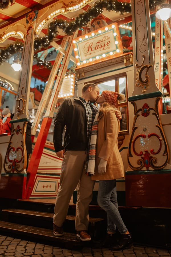 A man and a woman kiss by the entrance to the Christmas ferris wheel.