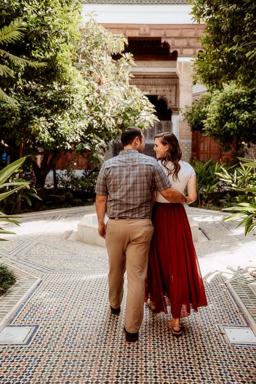 A man and a woman walk by each other in a beautiful courtyard in Marrakech.