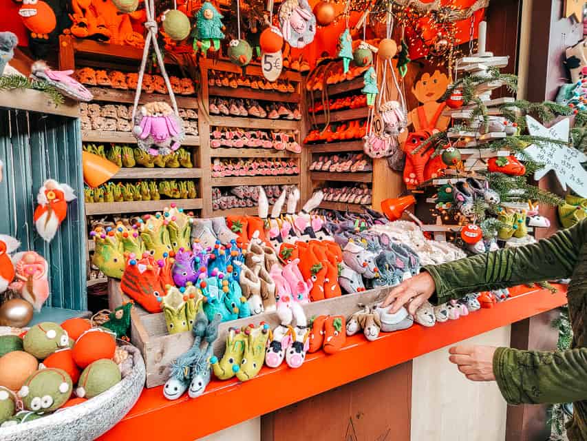 a close up of a red Christmas market stall, filled with soft little animal booties for kids.