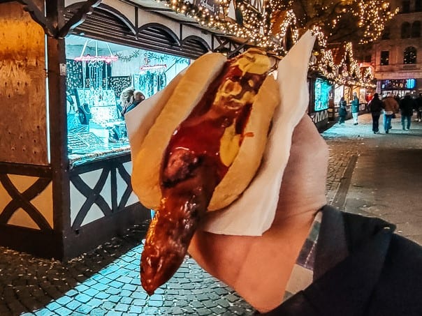 One of the most classic German foods - a grilled bratwurst on a bun in the St. Nicolas Market in Cologne.