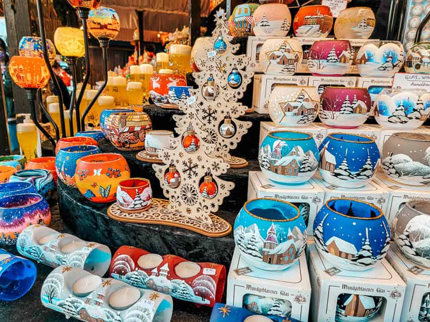 A stall selling a variety of vandles and small candle holders in a variety of shapes, colors, and sizes.