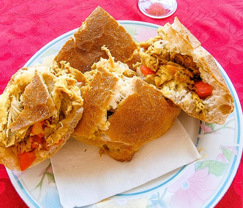 A Moroccan chicken sandwich consists of flaky bread filled with seasoned, shredded chicken and vegetables.