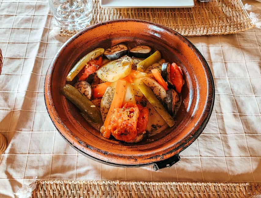 A Moroccan tagine dish with many vegetables featured (such as carrot, zucchini, and eggplant.