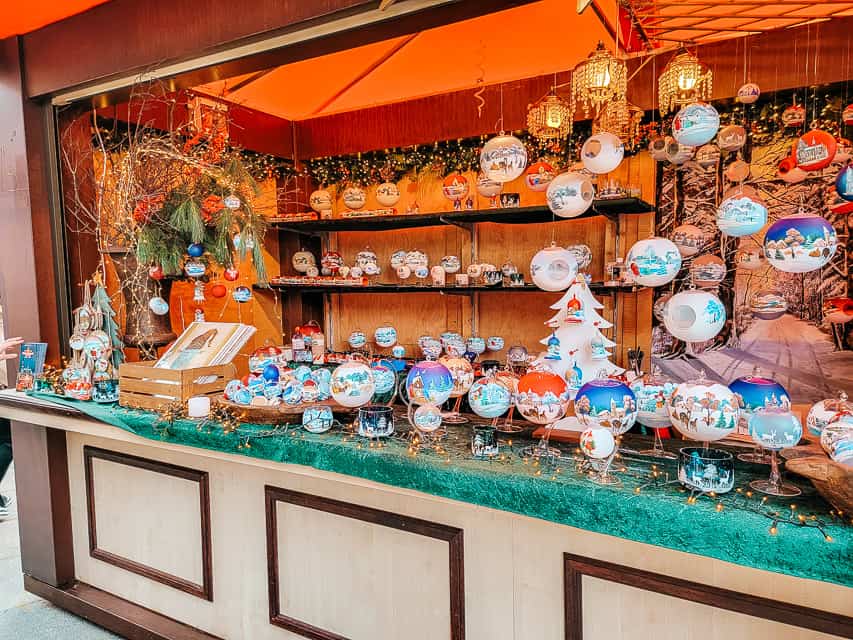 A close up of a christmas market stall, selling glass, circle ornaments.