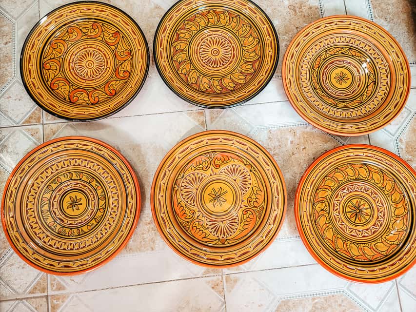 6 orange-yellow bowls with swirling designs on a floor in a shop in Marrakech, Morocco.