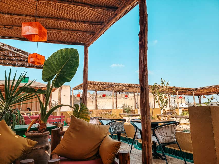 Shaded couches and chairs fill a patio at a Moroccan cafe.