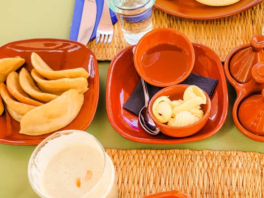 A plate of gazelle horns, a curved cookie, is served alongside honey and butter.