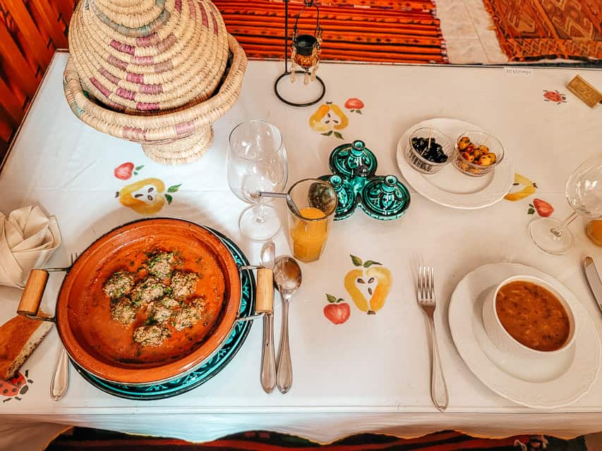 Kefta tagine and harira soup are served with a colorful basket holding bread nearby.