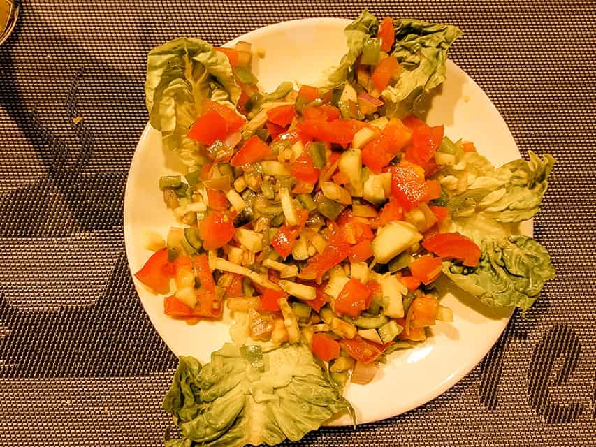 A plate of Moroccan salad - similar to pico de gallo - with diced tomatoes, onions, and peppers on lettuce and a vinaigrette.
