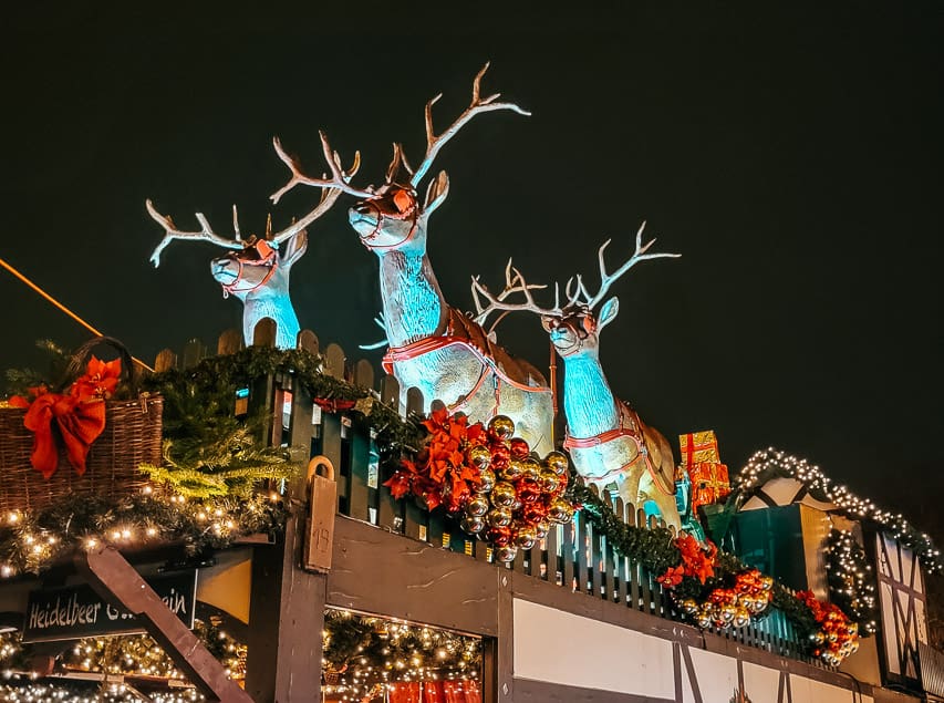 Statues of reindeer pulling the sleigh are on top of a stall in St. Nicolas Market.