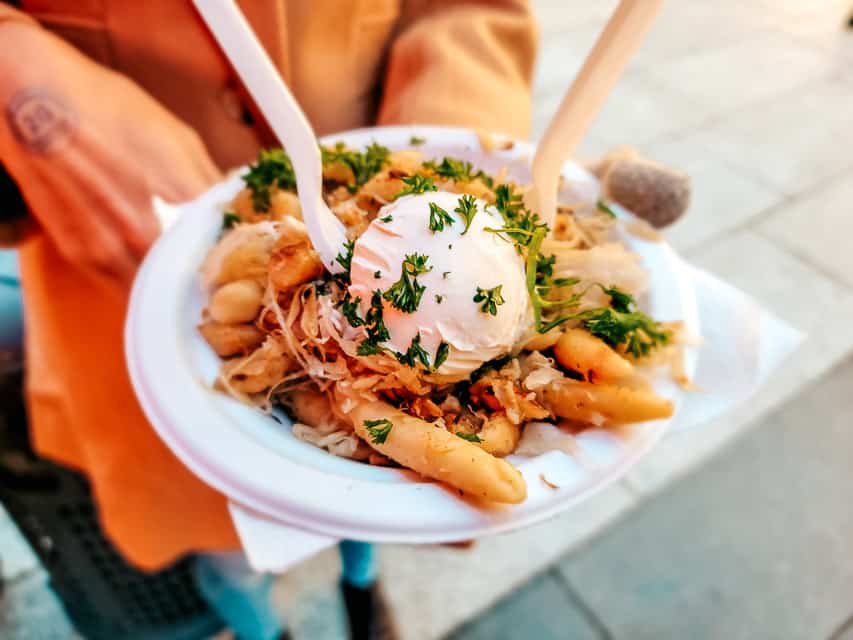 A paper bowl with potato noodles, sauerkraut, and a big dollop of creme fraiche - a traditional food to eat at the Cologne Christmas market.