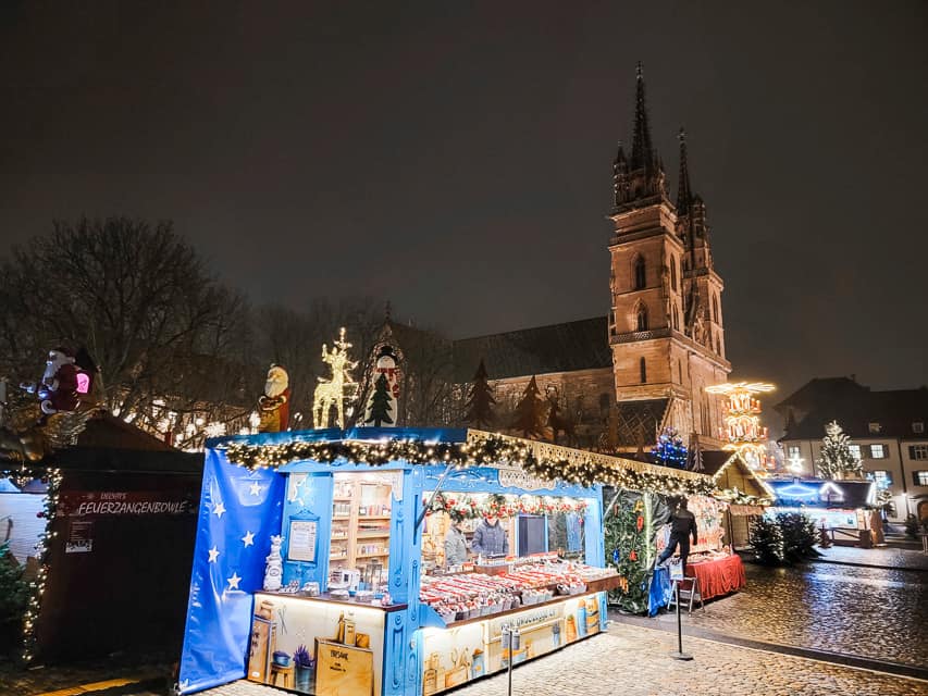 Stalls decorated with greenery are lit up in front of the Munster cathedral at night in Basel, Switzerland.