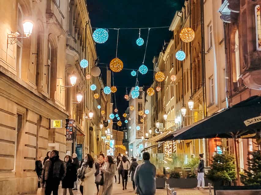 Gold and white lit balls are strung between upscale stone buildings in old town Luxembourg.