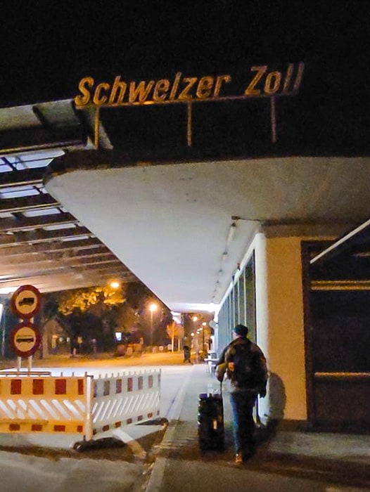 A man passes a toll booth with luggage.