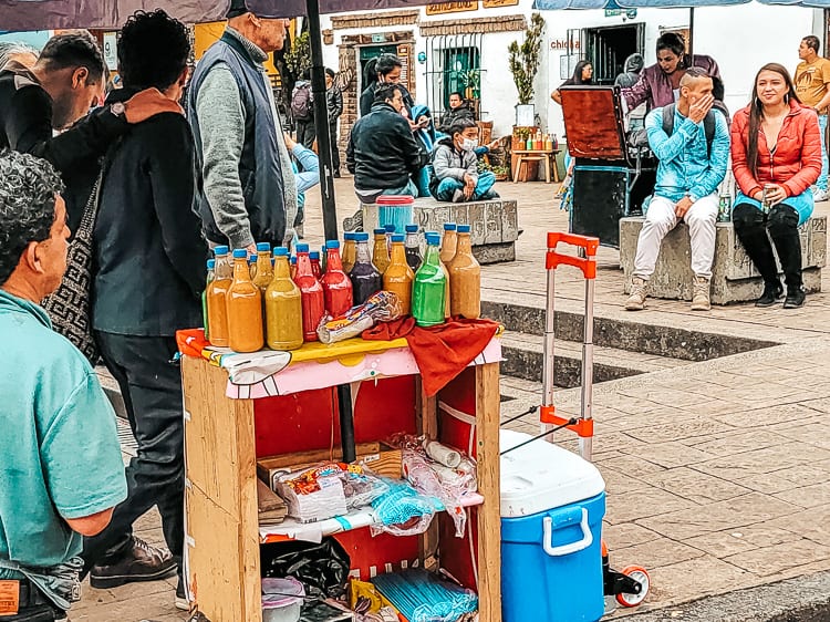 Picture of Chica stall in plaza. Bottles are multicolored due to added food dye. Chica is a traditional corn based drink in Colombia and South America.