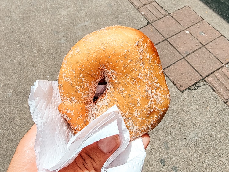 A hand is holding a sugar brushed donut. Inside is arequipe.