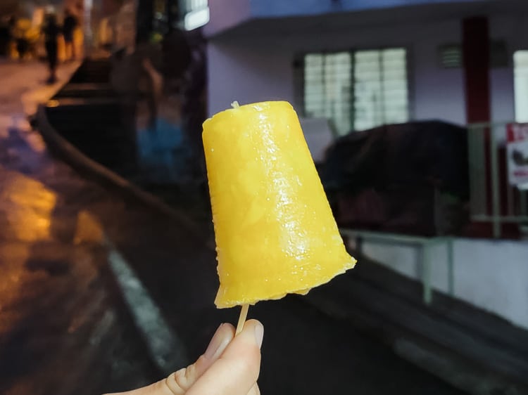 A hand is holding a Helados, a fruit and milk or water based popsicle.