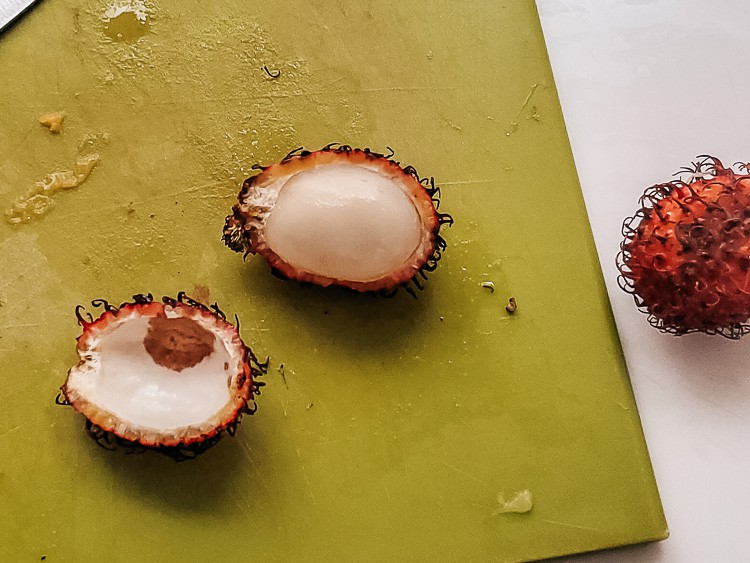 Lychee fruit from Colombia. A red, spiky fruit. White on the inside and surrounding a seed. Sweet fruit.