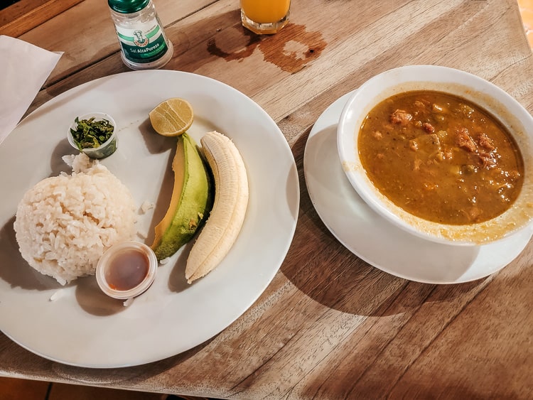A bowl of Mondogo soup along with a plate of rice, avocado, and banana.