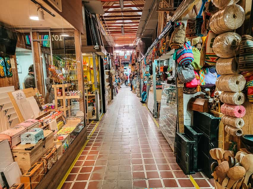 A narrow walkway through some shops, with a lot of different goods on display.