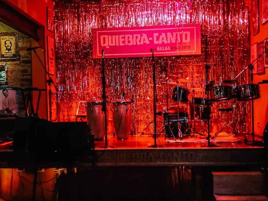 The stage of a salsa baer, with a piano and drums on stage.