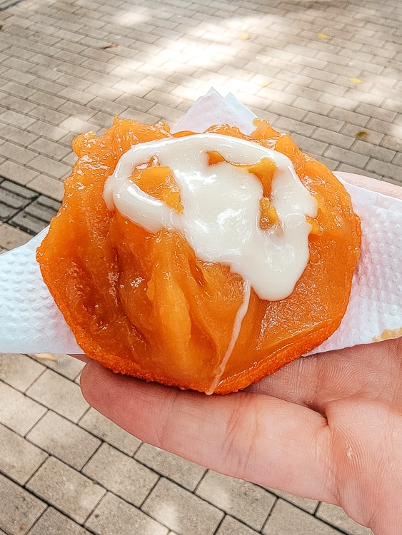 An orange that has been cut open and has a white frosting and different juices filled in the middle