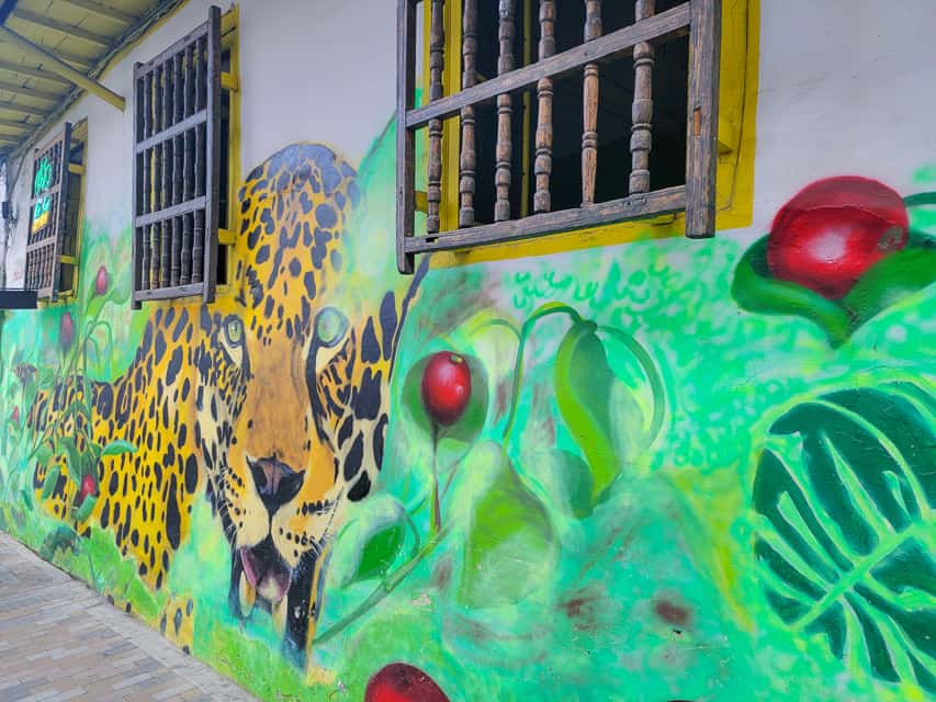 Street art in Bogota. This mural has a jaguar walking through greenery, with red berries scattered throughout the leaves.