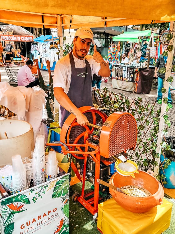 A man grinds fresh sugar cane juice.