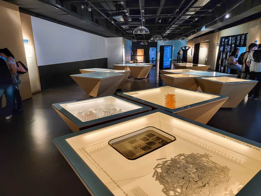 A very modern room with dark floors and different exibits showing information of the drug cartels and guerilla groups