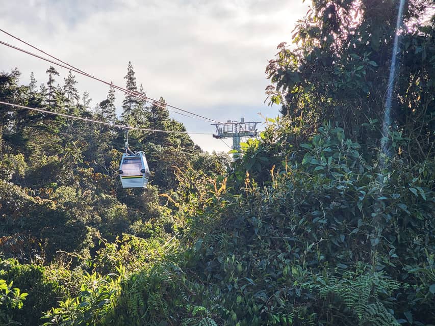 The mountain area with the poles and wires connecting the small rectangular cable cars.