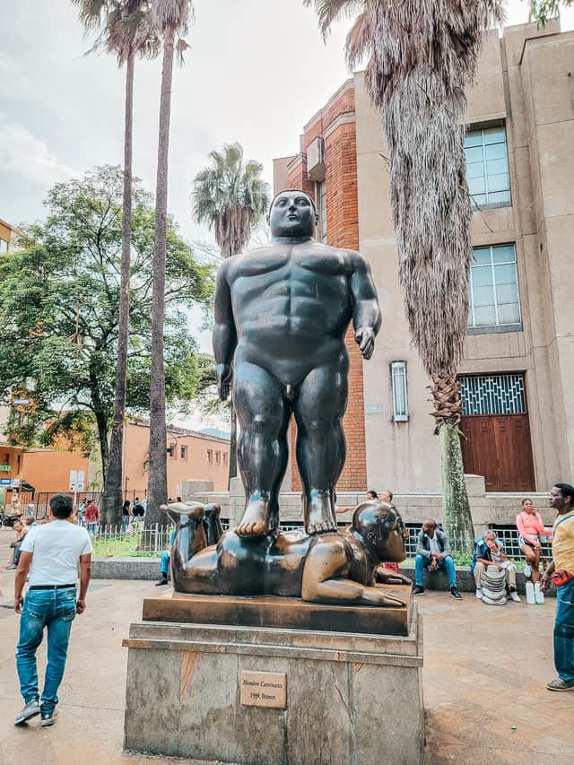 A silver statue with a bare chest stands on a child.