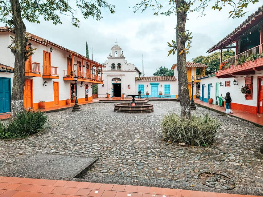 A small square with colorful buildings and a small fountain in the middle.