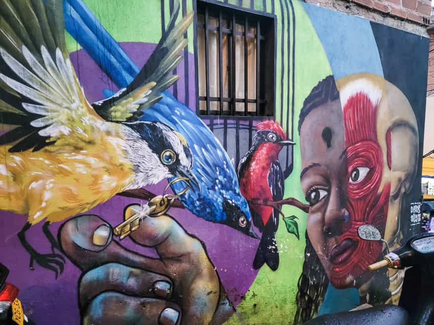 A mural of an African American woman holding a stick with different colored birds perched on it.