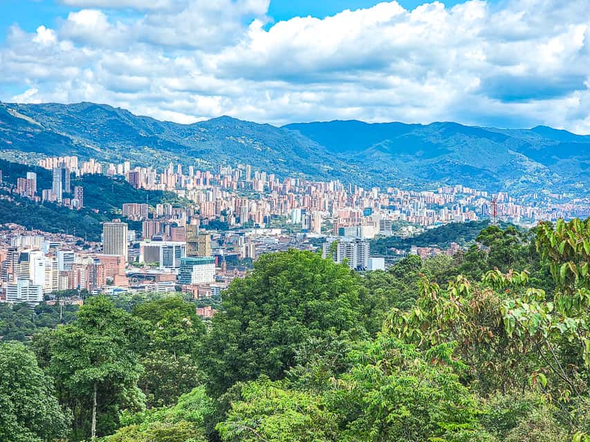 The view from the top of a mountain looking over the city and the mountain range.