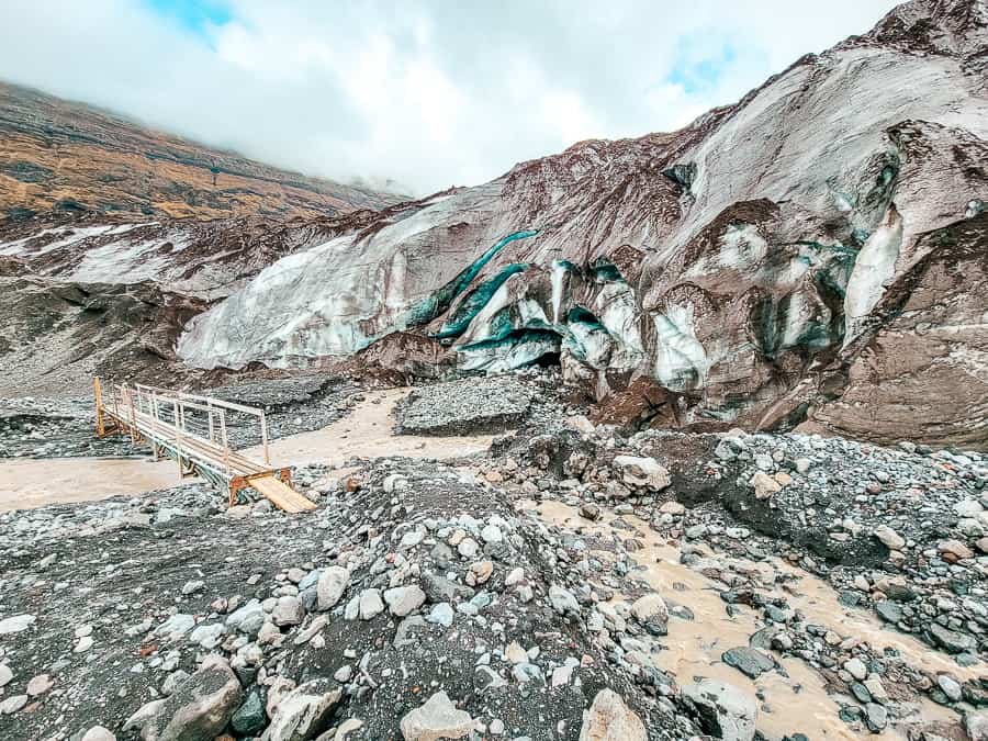 A mud, rock and ash path leads to the start of the Skaftafell glacier and too the side there are dark blue-green streaks with volcanic ash embedded with it.