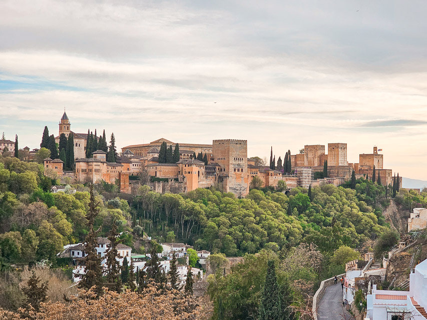Alhambra dominates this vista with orange stone walls and buildings standing out strongly against the hills of Granada.