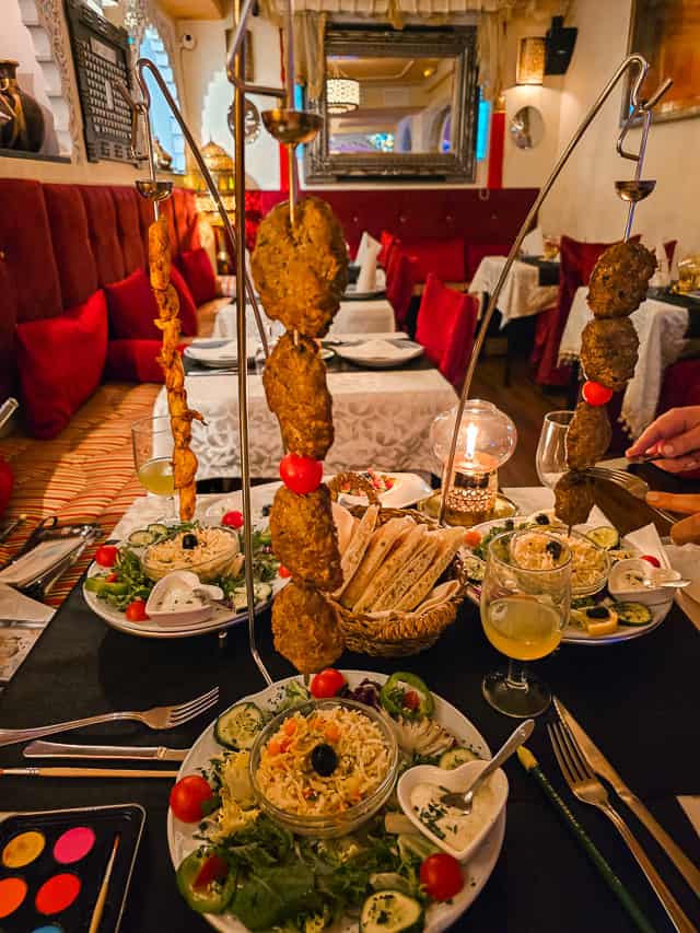 Dinner at a restaurant - skewers of meat hanging from a pool, a plate of rice and vegetables is under the hanging skewers. The great restaurants are one of the reasons that Granada is worth visiting.