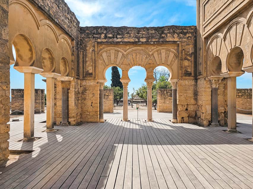 A stone room with no roof and lots of arches and black erosion near the top.