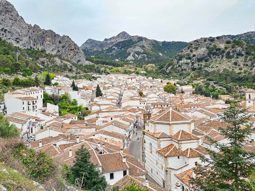 white houses topped with brown clay roofs sit in the little village of Grazalema, surounded by mountain peaks