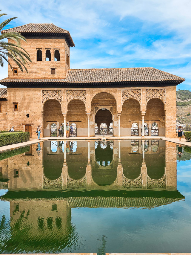 A reflecting pool in the foreground shows the reflection of one building in the Nasrid Palaces.