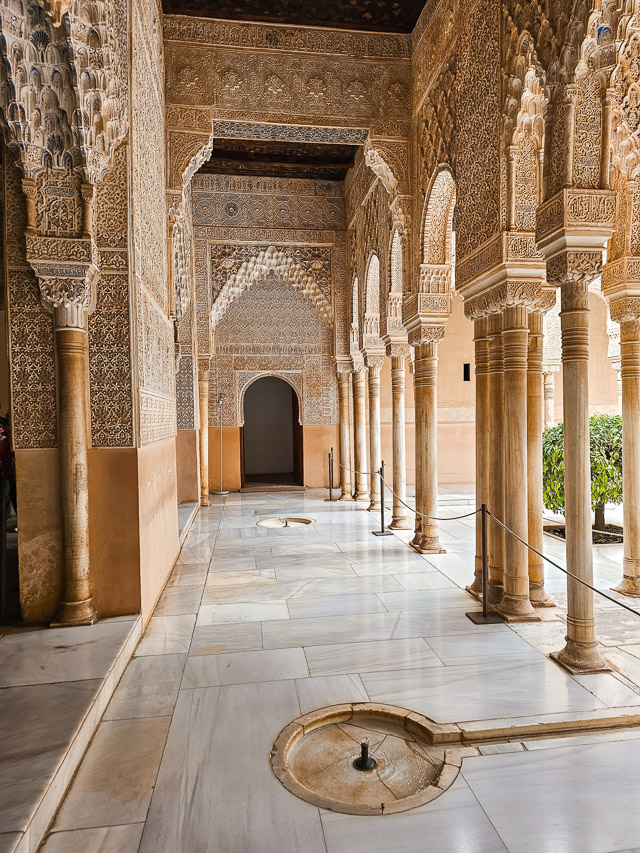 Stunning carved and decorated stucco forms a walkway with marbles tile and stone pillars.